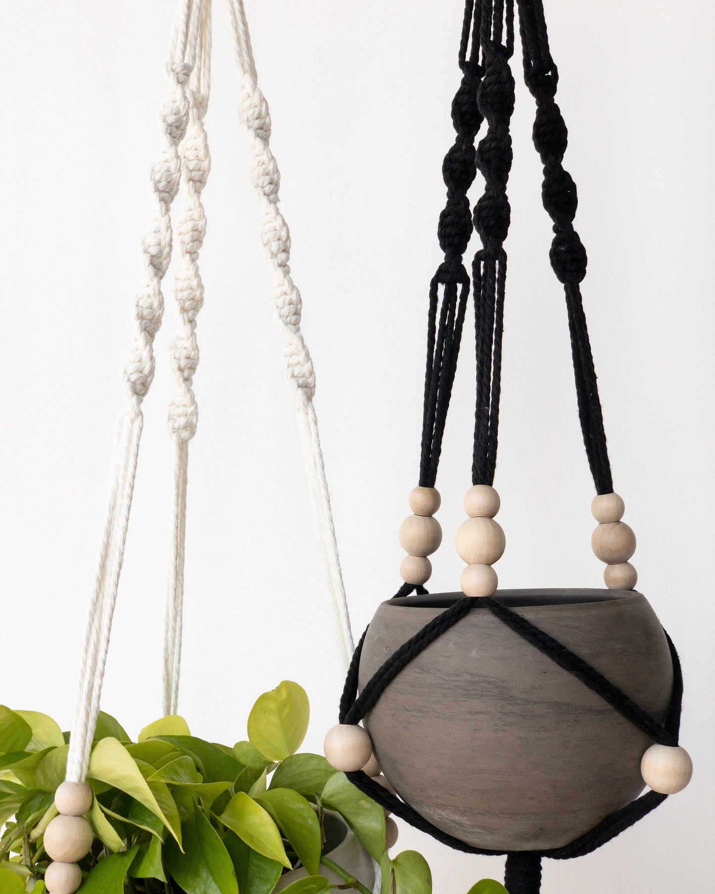 two plant hangers with a spiral section at the top and movable beads around the pots.