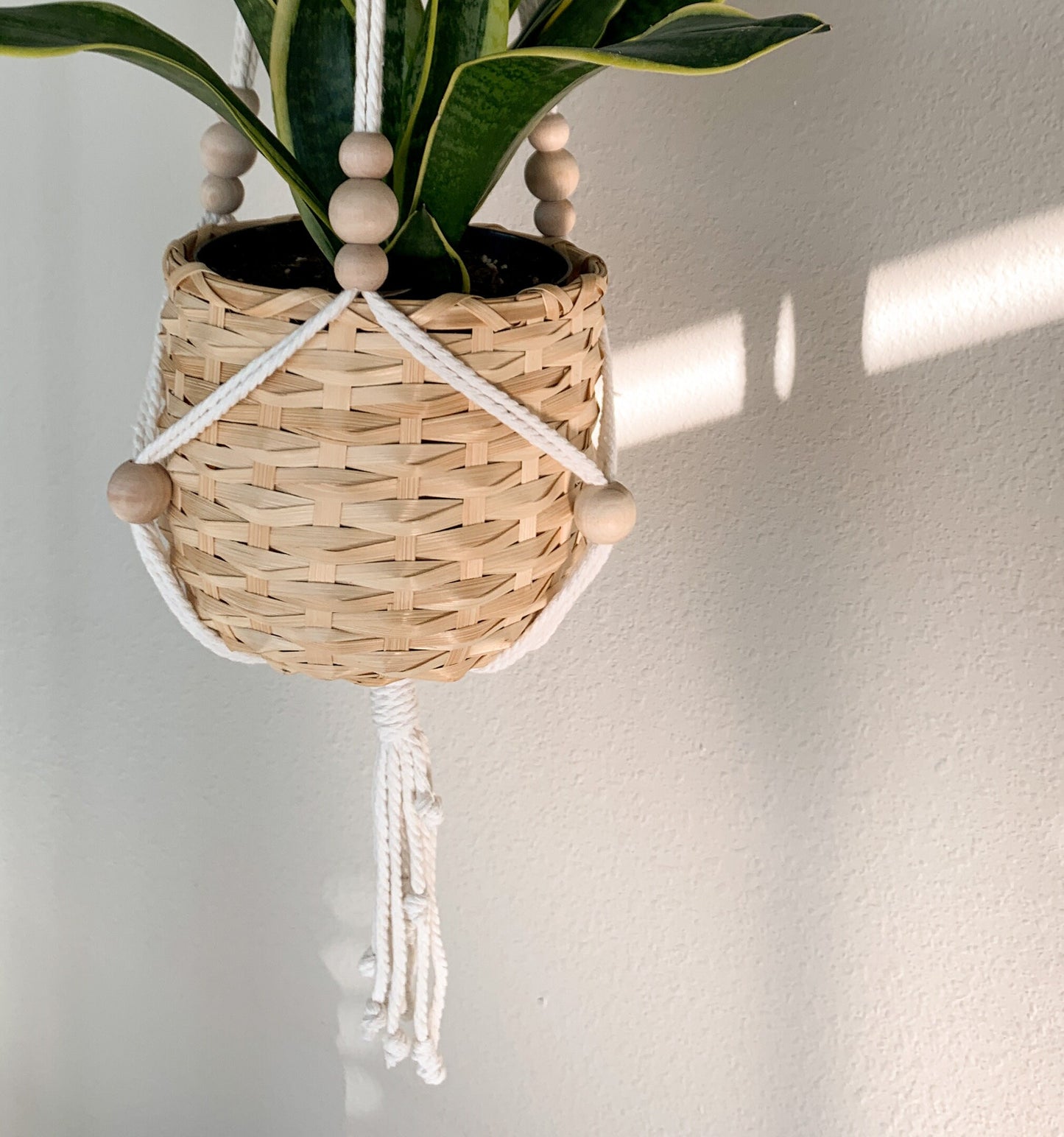 Close up of a boho plant hanger styled with a wicker pot