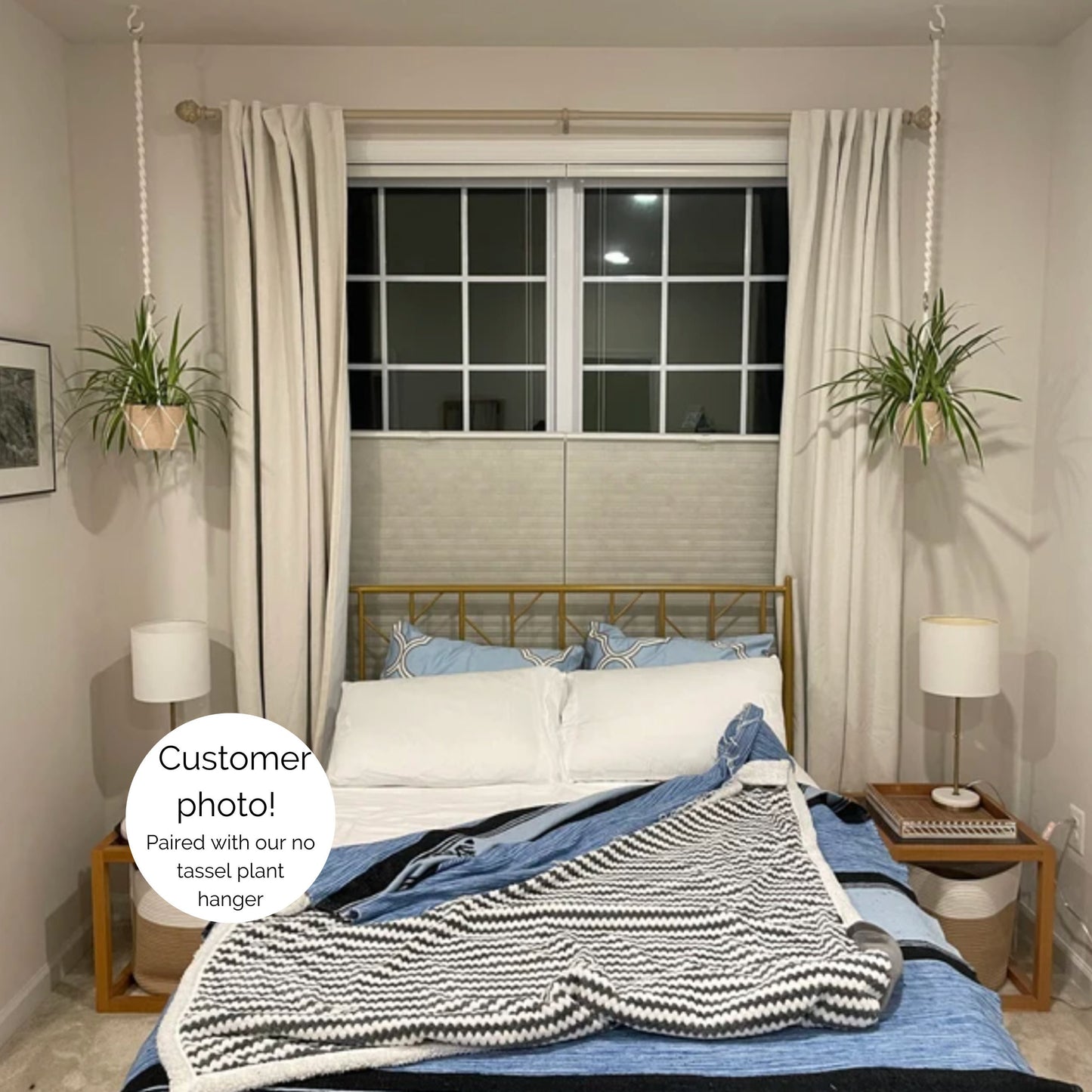 A styled bedroom scene showing two plants hanging from the ceiling on either side of the bed. The plant hangers are attached to extra long extenders and do not have a tassel.