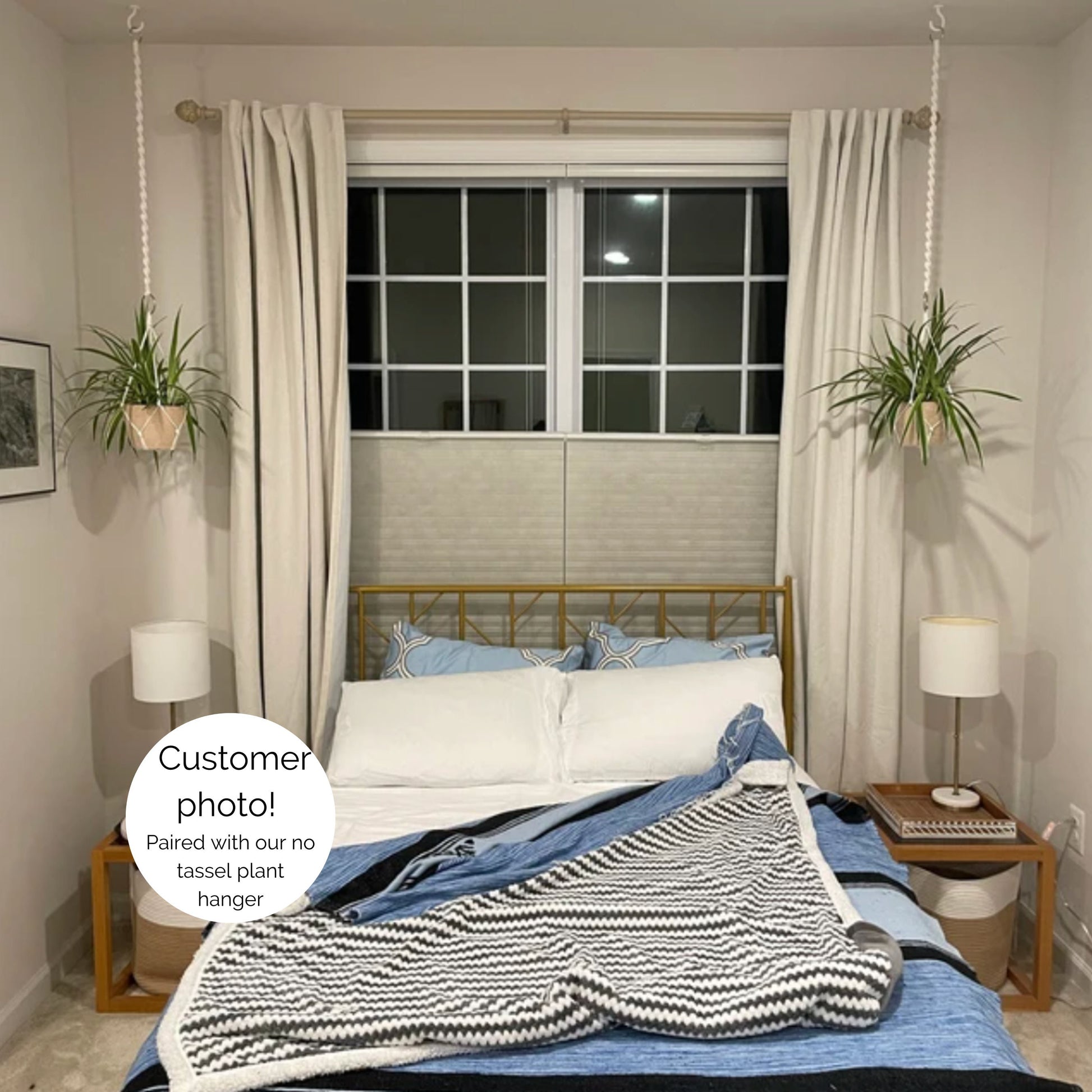 A styled bedroom scene showing two plants hanging from the ceiling on either side of the bed. The plant hangers are attached to extra long extenders and do not have a tassel.