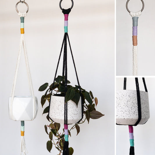 Sleek modern macrame plant hangers. They each have 8 straight straps supporting the pot. The top and bottom of the cords have a sleek wrap in a color block pattern with colors. The left has white as the main color, the right main color is black.